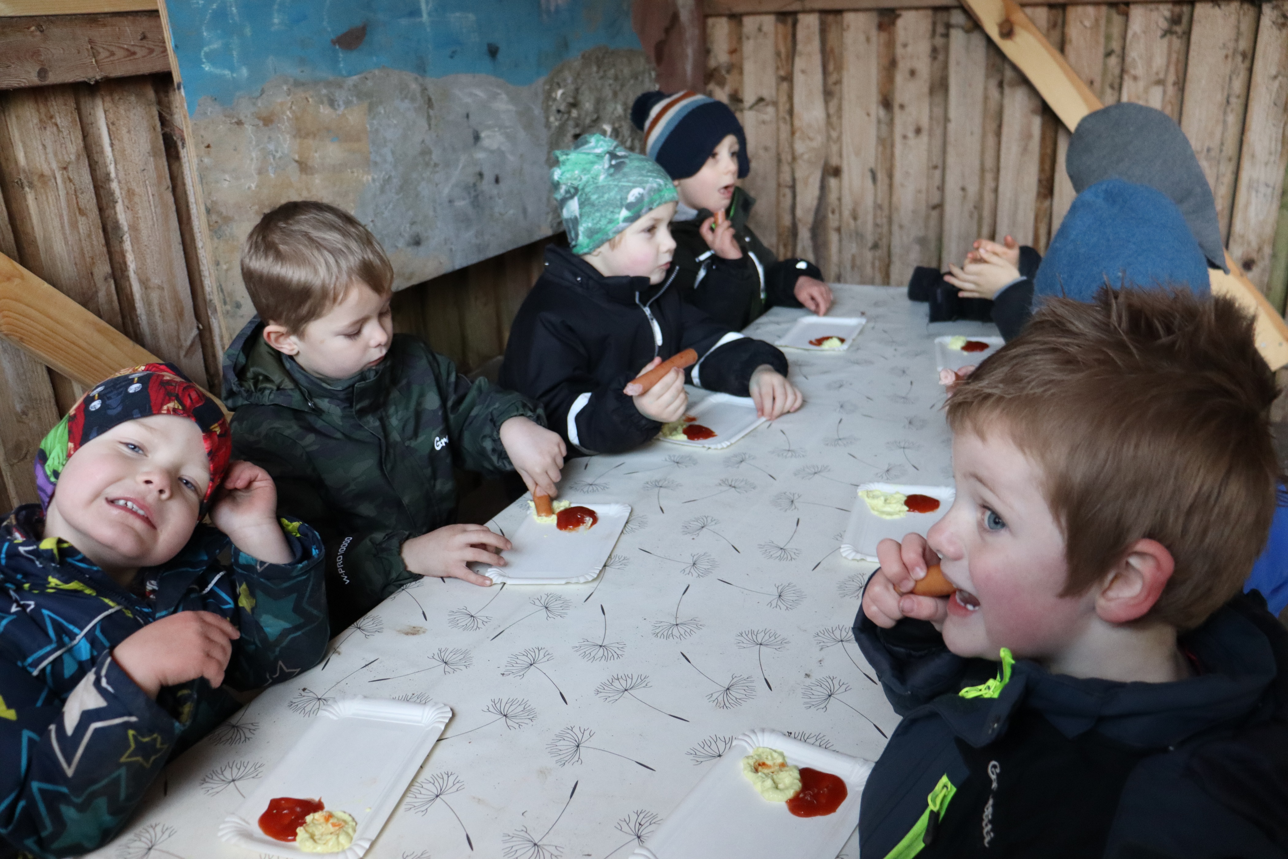 Børn spiser pølser med brød udenfor